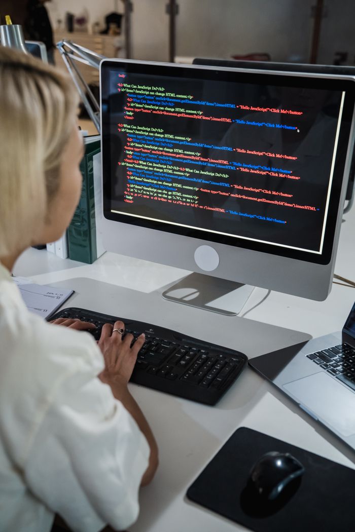 Crafting Captivating Headlines: Your awesome post title goes here A female programmer writing code on a desktop computer in an office setting with a focus on technology and IT development.